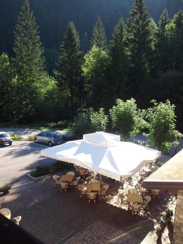 a white table and chairs with an umbrella at Albergo Nuoitas in Forni di Sopra