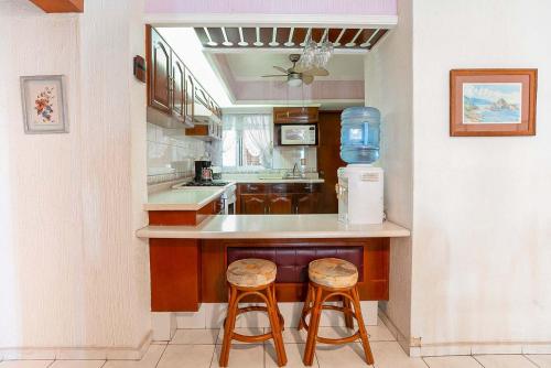 a kitchen with a counter and two stools in it at Playa Azul Apt with Sea views & Pool in Manzanillo