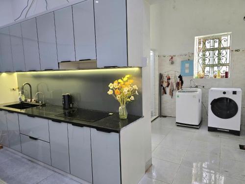 a kitchen with white cabinets and a vase of flowers on the counter at Long tearm rental-Whole house with swimming pool in Kỳ Vĩ