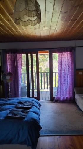 a bedroom with purple curtains and a bed and a window at Cheerful Bush House in Hepburn Springs