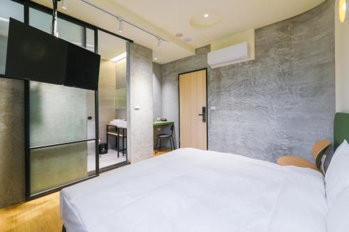 a bedroom with a large white bed and a desk at Green Hot Spring Hotel in Jiaoxi
