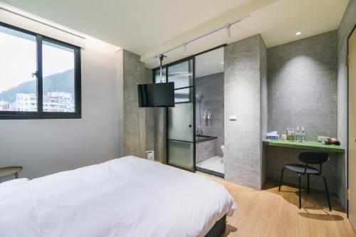 a bedroom with a white bed and a bathroom at Green Hot Spring Hotel in Jiaoxi