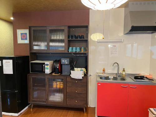 a small kitchen with a sink and a microwave at Hanamachi guest house in Osaka