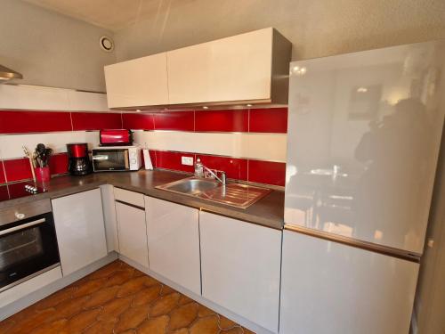 - une petite cuisine avec des placards blancs et des murs rouges dans l'établissement Studio avec coin-nuit, terrasse et parking privé près du centre de Sainte-Maxime, Golfe de Saint-Tropez - FR-1-780-60, à Sainte-Maxime