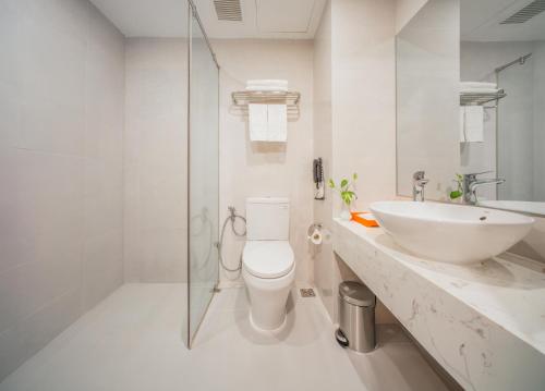 a white bathroom with a toilet and a sink at Libra Hotel Nha Trang in Nha Trang