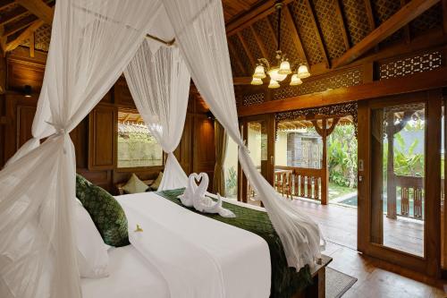 a bedroom with a bed with mosquito net at Suraya Ubud Villa in Ubud