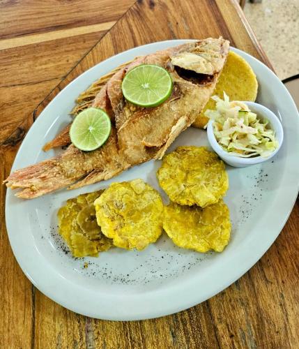 a plate of food with fish and chips and lime slices at Habitación sencilla con desayuno - La Casona Hotel in La Pintada