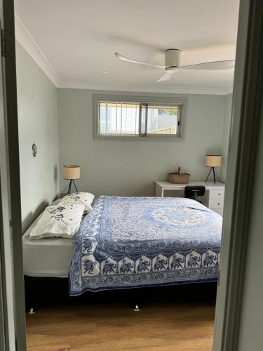 a small bedroom with a bed and a window at Coastal Calm Entire Top Floor of House Private Entrance and ammenities in South West Rocks