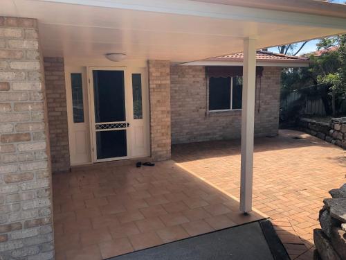 a patio with a white door and a brick wall at Coastal Calm Entire Top Floor of House Private Entrance and ammenities in South West Rocks