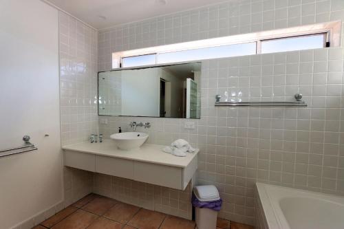 Un baño con lavabo, espejo y bañera. en Sandcastles 1 - Beach front, en Bargara