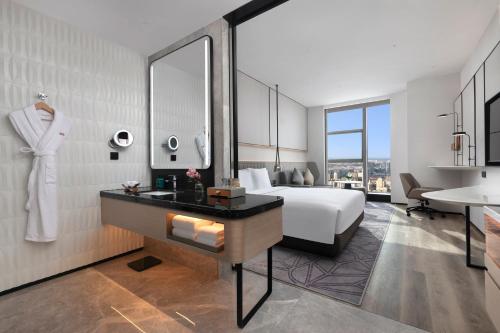 a bedroom with a bed and a bathroom with a sink at Crowne Plaza Taizhou City Center by IHG in Taizhou