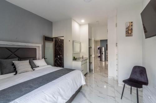 une chambre avec un grand lit et une chaise dans l'établissement Suite Balcón Refugio Moderno en Zapotlanejo 201, à Zapotlanejo