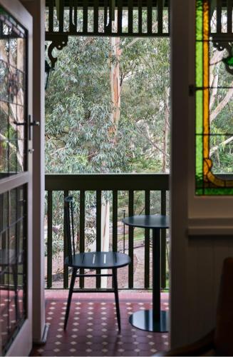 a table and a chair on a porch with a stained glass window at Silkari The Charrington at Chatswood in Sydney