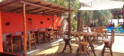a restaurant with tables and chairs and a red wall at El Belga Loco in Las Peñitas