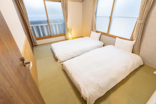 two beds in a room with two windows at Miro Fusimiinari Tei South in Kyōto