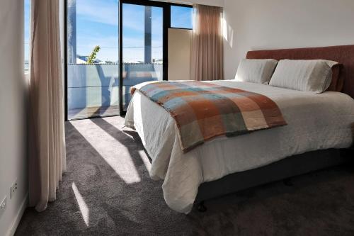 Un dormitorio con una cama y una ventana grande. en Frankie Luxury pool house Geelong Sleeps 12 Close to GMHBA cafes restaurants shops schools, en Newtown and Chilwell