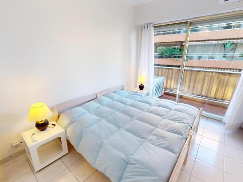 un grand lit dans une chambre avec une grande fenêtre dans l'établissement Spacieux 2P centre Menton avec terrasse, clim et parking privé - FR-1-196-370, à Menton