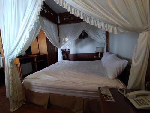 a bedroom with a canopy bed with white curtains at Victoria Peak Garden Suburb in Renai