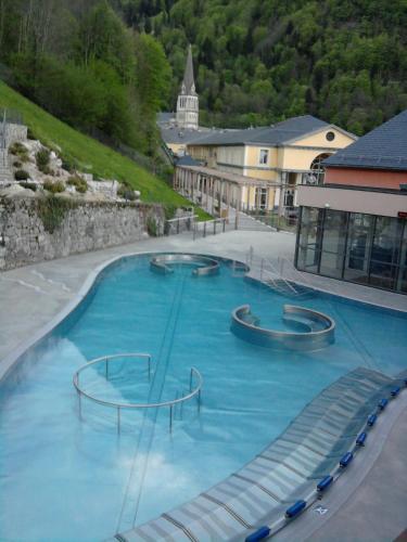 une grande piscine d'eau bleue en face d'un bâtiment dans l'établissement Vacances Perennes, à Cauterets