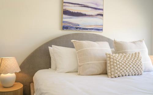 a bed with white pillows and a painting on the wall at StayAU 5BRM Coastal Retreat for Families Baldivis in Baldivis