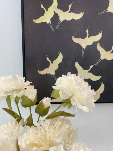 a vase with white flowers and a picture of birds at The Grand Diamond C Tuong Mai in Hanoi