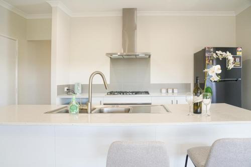 a white kitchen with a sink and a refrigerator at StayAU 5BRM Coastal Retreat for Families Baldivis in Baldivis