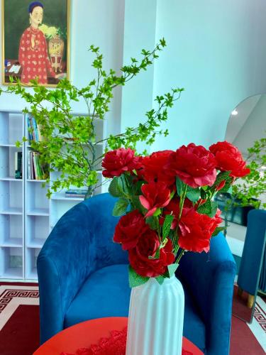 a white vase filled with red flowers on a table at The Grand Diamond C Tuong Mai in Hanoi