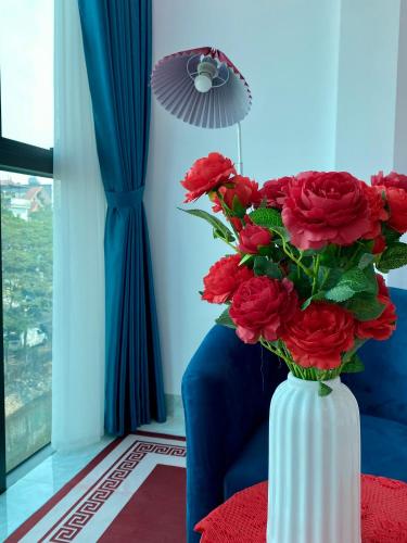 a white vase filled with red flowers in a room at The Grand Diamond C Tuong Mai in Hanoi
