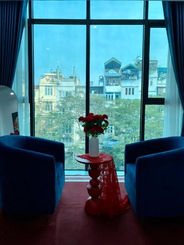 a room with a large window with a table with flowers on it at The Grand Diamond C Tuong Mai in Hanoi