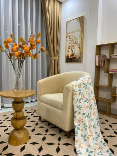 a living room with a chair and a table with a vase of flowers at The Grand Diamond C Tuong Mai in Hanoi