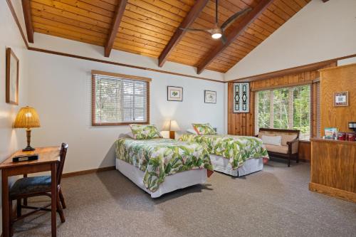 a bedroom with two beds and a table and a desk at Kilauea Lodge and Restaurant in Volcano