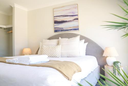 a bedroom with a white bed with a painting on the wall at StayAU 5BRM Coastal Retreat for Families Baldivis in Baldivis