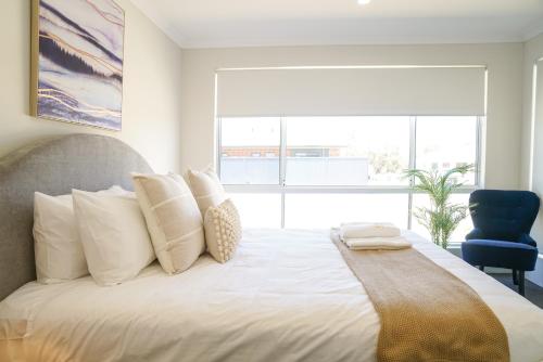 a bedroom with a large bed with white pillows at StayAU 5BRM Coastal Retreat for Families Baldivis in Baldivis