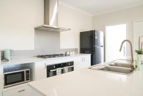 a white kitchen with a sink and a refrigerator at StayAU 5BRM Coastal Retreat for Families Baldivis in Baldivis