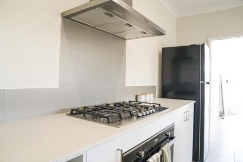 a kitchen with a stove and a refrigerator at StayAU 5BRM Coastal Retreat for Families Baldivis in Baldivis