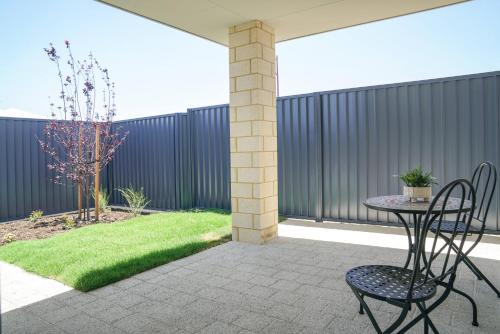 a patio with two chairs and a table and grass at StayAU 5BRM Coastal Retreat for Families Baldivis in Baldivis