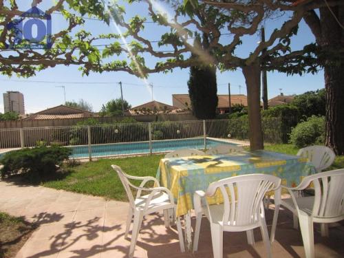 - une table et des chaises dans une cour avec une piscine dans l'établissement Villa spacieuse 9 pers avec piscine privée, grand jardin, parking à Sérignan - FR-1-781-71, à Sérignan