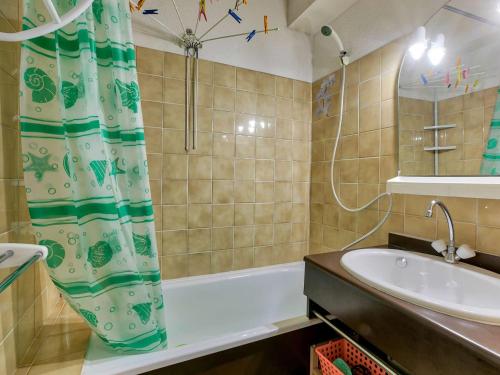 a bathroom with a tub and a sink and a shower curtain at Appartement cosy pour 4 à Gourette, balcon sud-ouest et services optionnels - FR-1-400-134 in Eaux-Bonnes