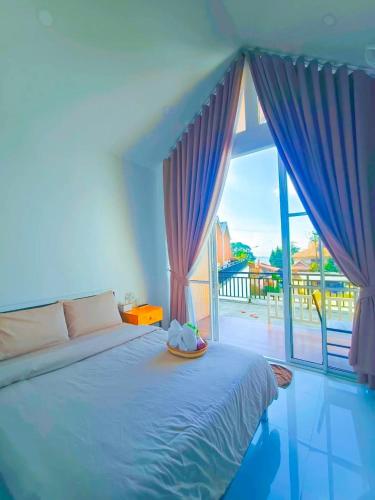 a bedroom with a bed and a large window at ไวท์เฮาส์ ภูชี้ฟ้า in Ban Tin Pet