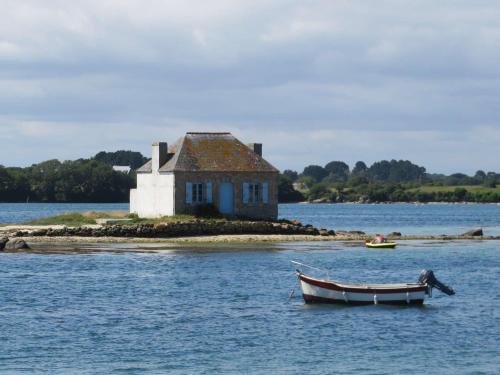 un bateau dans l'eau devant une maison dans l'établissement Studio moderne à Plouhinec, WIFI, parking, animaux acceptés - FR-1-479-184, à Plouhinec