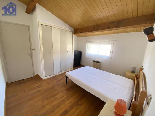 une chambre avec un grand lit blanc et du parquet dans l'établissement Grande villa 10 pers, 5 ch, proche plage, au calme - FR-1-781-70, à Valras-Plage