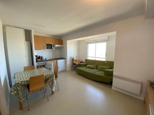 un salon avec un canapé vert et une table dans l'établissement Appartement 7 pers avec équipement complet à Arette - FR-1-602-118, à Arette