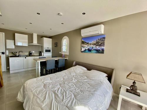 Cet appartement comprend une chambre avec un lit blanc et une cuisine. dans l'établissement T2 Mezzanine au Lavandou, proche plage, climatisé - FR-1-816-8, au Lavandou