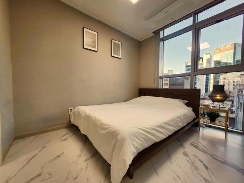 a bedroom with a bed and a large window at Majestic Seoul Stay Central in Seoul