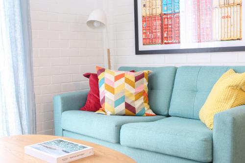 a blue couch with a colorful pillow and a table at City Living in Fremantle