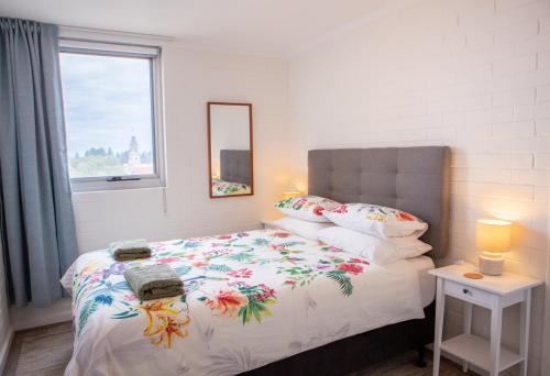 a bedroom with a bed with a floral bedspread and a window at City Living in Fremantle