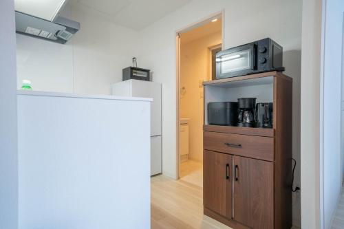 a kitchen with a microwave on top of a wooden cabinet at Altiplano in Sapporo