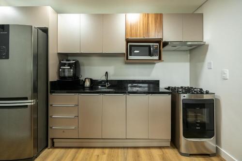 a kitchen with a stainless steel refrigerator and microwave at Riviera Concept 2 dorm by Achei Camboriú in Itajaí