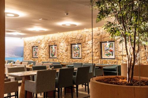 a restaurant with tables and chairs and a stone wall at Riviera Concept 2 dorm by Achei Camboriú in Itajaí