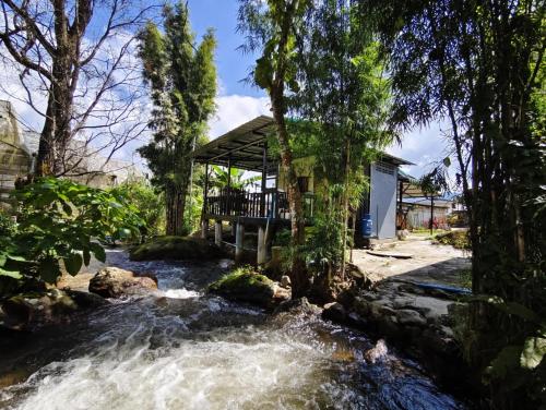 a river in front of a house with a bridge at อินทนนท์ เล่าจู in Ban Na Yang